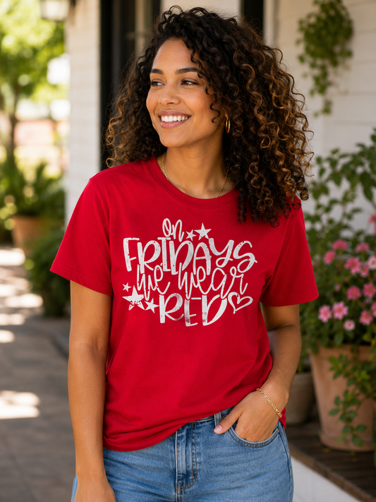 Woman wearing a red T-shirt featuring the phrase "On Fridays We Wear Red" in distressed white lettering with patriotic stars while smiling outdoors.